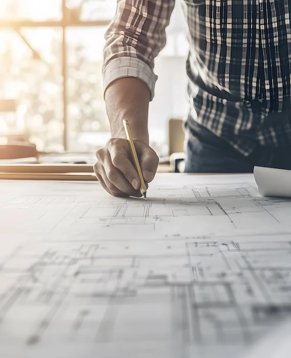 ingénieur freelance - un homme penché sur une table de travail écrivant sur des plans d'architecte